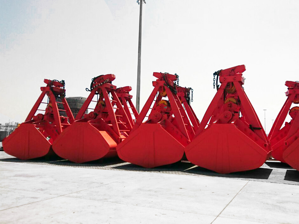 Series of Rapidpack clamshell grabs lined up outdoors, heavy-duty hydraulic grips open above surface