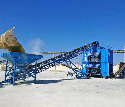 A blue Rapidpack in-feed conveyor system positioned outdoors on a concrete surface, featuring a sloping belt structure supported by a metal frame.