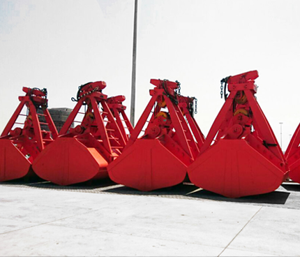 Rapidpack wire-rope grab suspended by crane, poised to collect dry bulk materials in a port environment